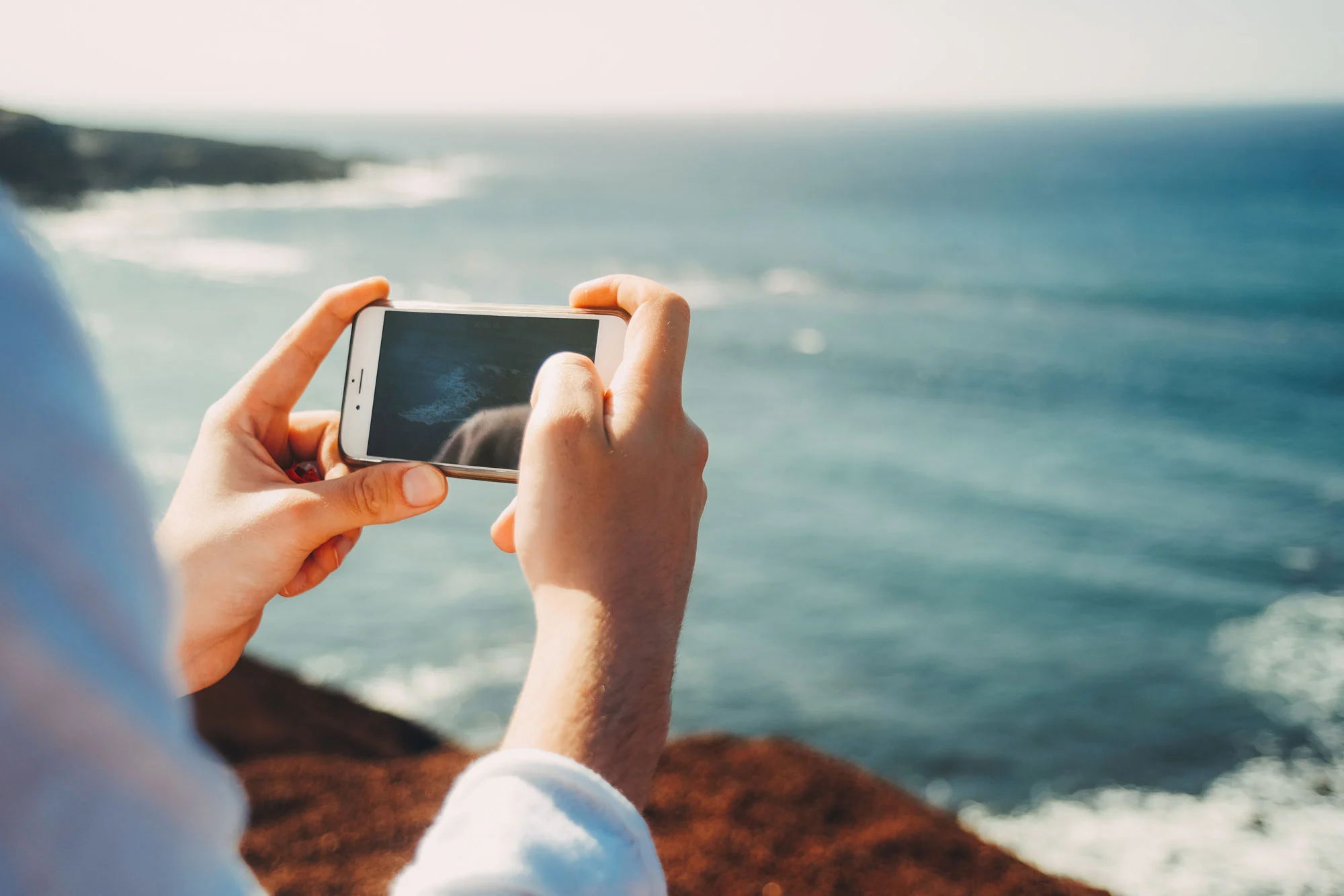 woman holding a phone at a remote beach