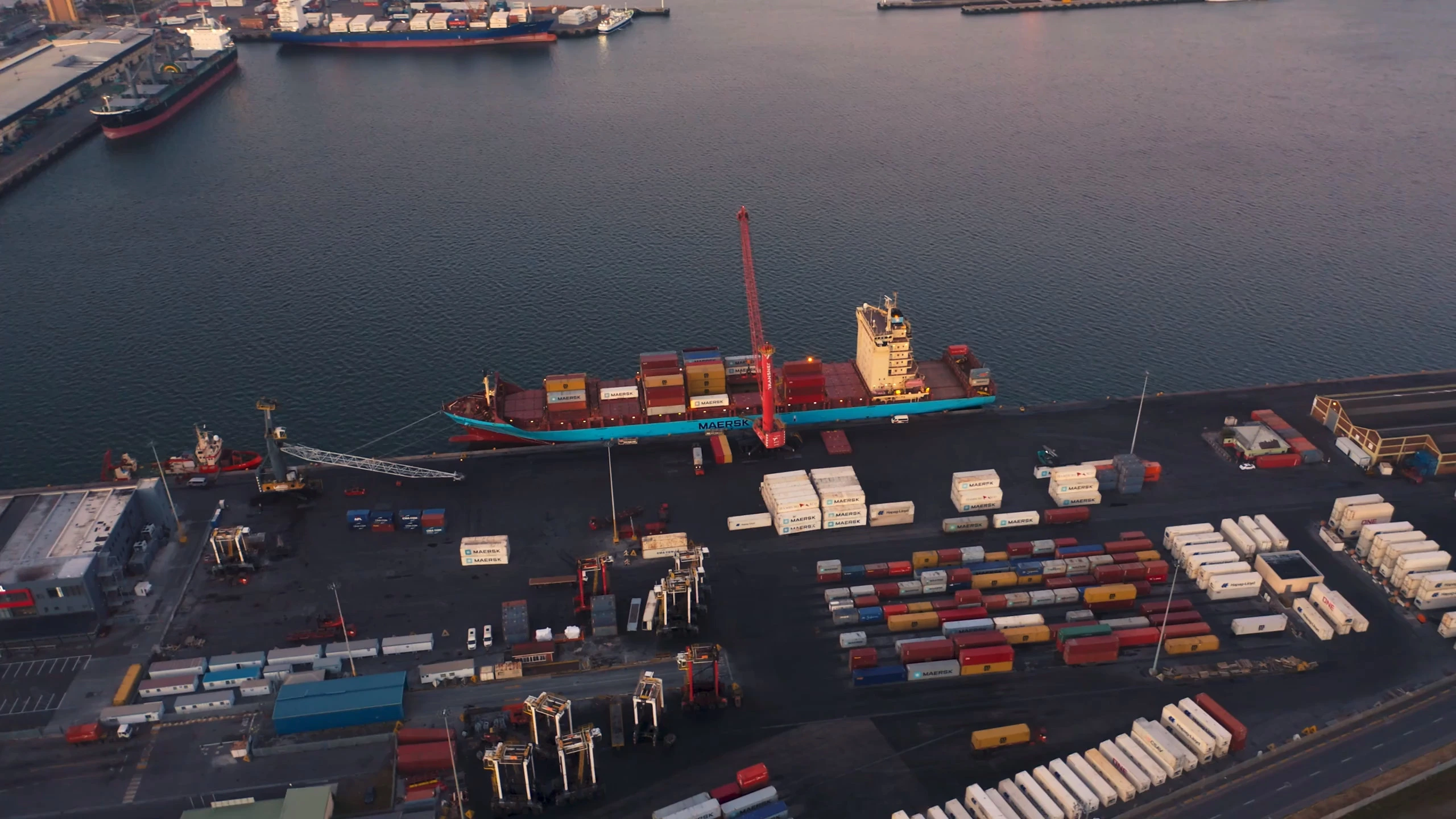 a cargo ship against a dock underneath a crane